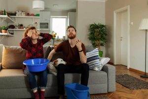 A family catching water leaking from roof in buckets