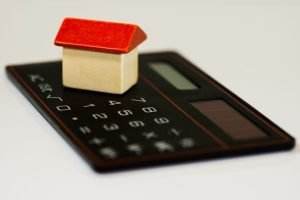 a wooden house on a calculator