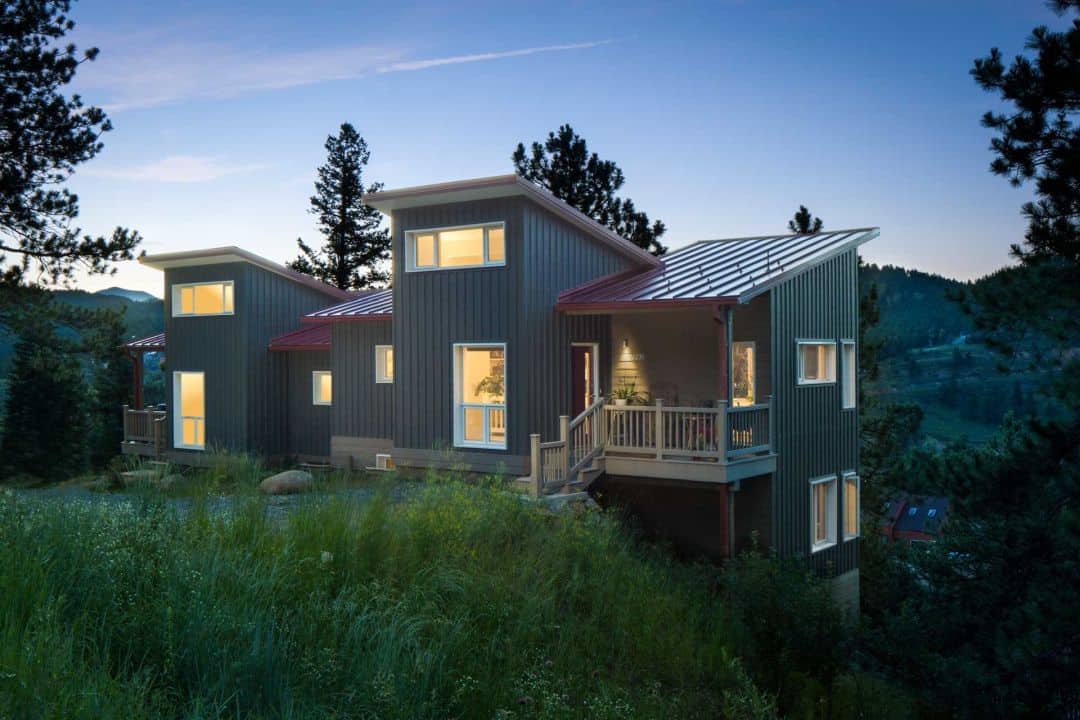 a trendy modern home with dark green siding