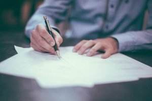 man signs insurance papers on desk