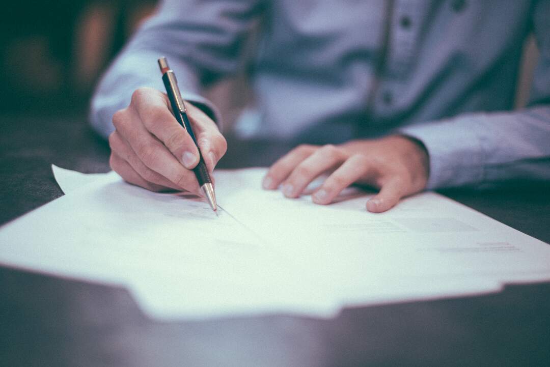 man signs insurance papers on desk