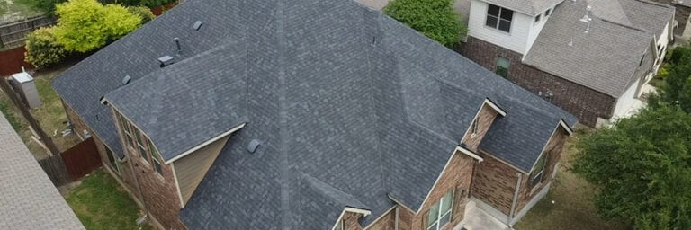 Aerial view of new gray shingle roof installed on a brick house by Dolan Roofing & Construction in San Antonio
